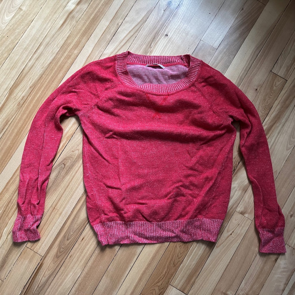 chandail rouge en tricot déposé sur un plancher